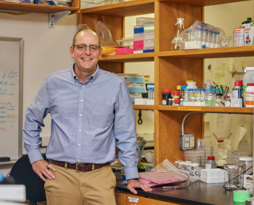 Dr. Ben Van Mooy standing in his lab, surrounded by equipment.